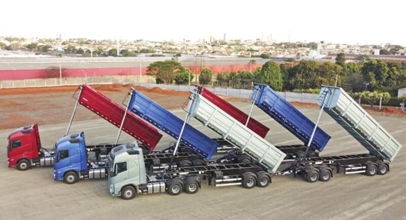 Caminhões parados e com a caçamba elevada, demonstrando a potência do kit hidráulico.